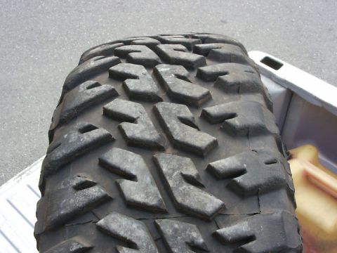 1990 Ford Bronco - A off-road tire is shown in detail, resting in the cargo area of a vehicle.