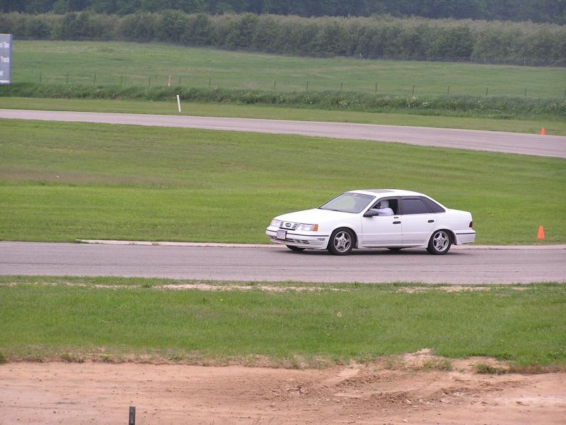 White sedan with tinted windows on a racetrack, side view. Appears to be a 1995 model