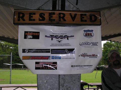 1998 Ford Taurus - A sign displays various sponsor logos including 'Running of the Bulls' and Ford, under a 'RESERVED' sign.