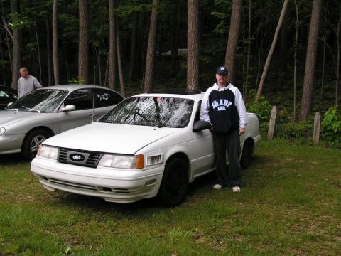 1998 Ford Taurus - A white Ford Taurus is parked on grass with trees in the background.