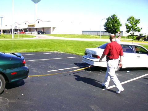 1998 Ford Taurus - A man walks between two cars, one of which is being towed in a parking lot.