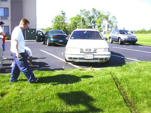 1998 Ford Taurus - A white sedan is parked in a lot with other vehicles. The front bumper appears damaged.