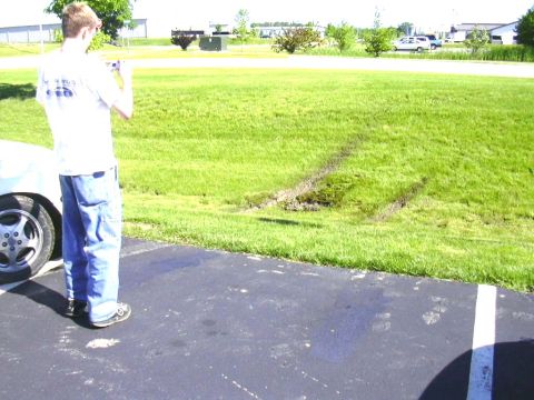 1998 Ford Taurus - Tire tracks are visible on the grass where a vehicle has driven off the paved surface.