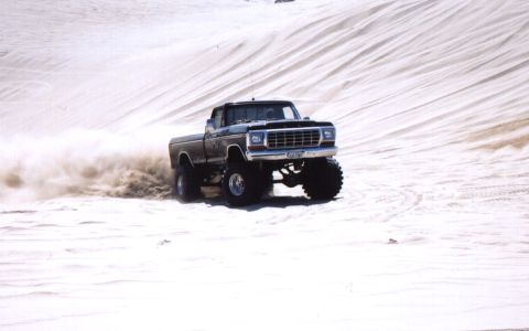 2000 Ford F-450 - Pickup truck driving through sand dunes, kicking up a cloud of dust.