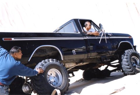 2000 Ford F-450 - This modified pickup truck, likely from the 1970s, has been heavily customized with oversized tires and a lifted suspension.