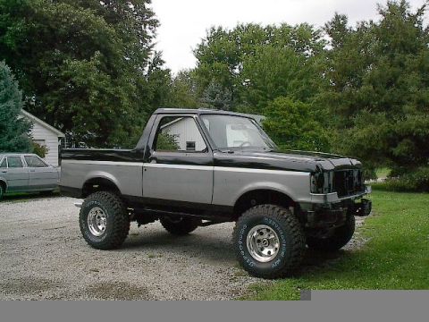 1989 Ford Bronco - This lifted Ford Bronco features a two-tone paint scheme and aftermarket wheels, with its front grille removed.