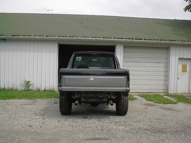 Rear view of a black and silver pickup truck, possibly a Ford Bronco from the 1980s