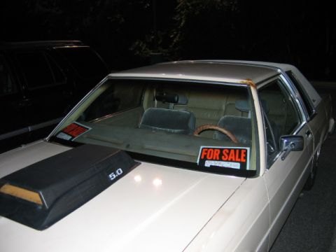1985 Ford LTD Crown Victoria - A cream-colored sedan, possibly a Ford, is parked at night with 'For Sale' signs visible through the windshield.