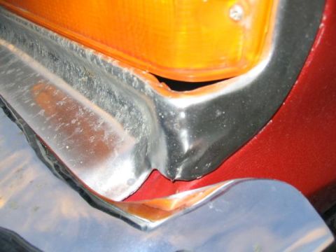 1979 Ford F-150 - Close-up of the front corner of a red 1979 Ford F-150, showing the turn signal and chrome bumper.
