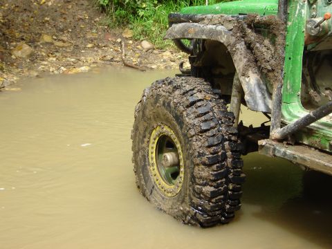 1992 Ford Bronco - This heavily modified off-road vehicle is navigating through a muddy water obstacle.