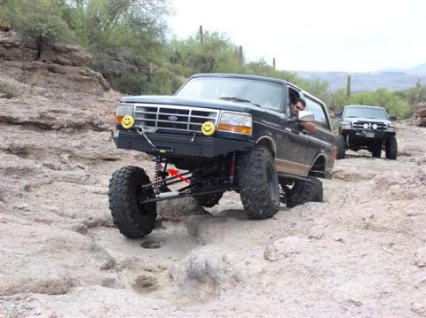 1994 Ford Bronco - Two SUVs, including a modified 1994 Ford Bronco, tackle a challenging rocky trail.