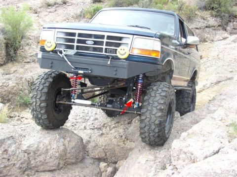 1994 Ford Bronco - This modified Ford Bronco is tackling a challenging off-road trail with its suspension articulated over large rocks.