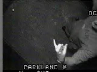 1985 Ford Bronco - Grainy black-and-white surveillance-style video still captioned 'PARKLANE W' along the bottom edge, showing a person in a dark hooded top r…