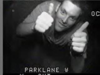 1985 Ford Bronco - Grainy black-and-white surveillance-style video still captioned 'PARKLANE W' at the bottom, showing a smiling person in a dark shirt giving…