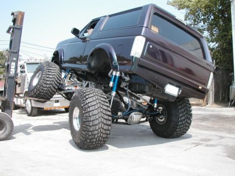 1994 Ford Bronco - A lifted 1994 Ford Bronco with oversized off-road tires is being loaded onto a flatbed truck by a forklift.