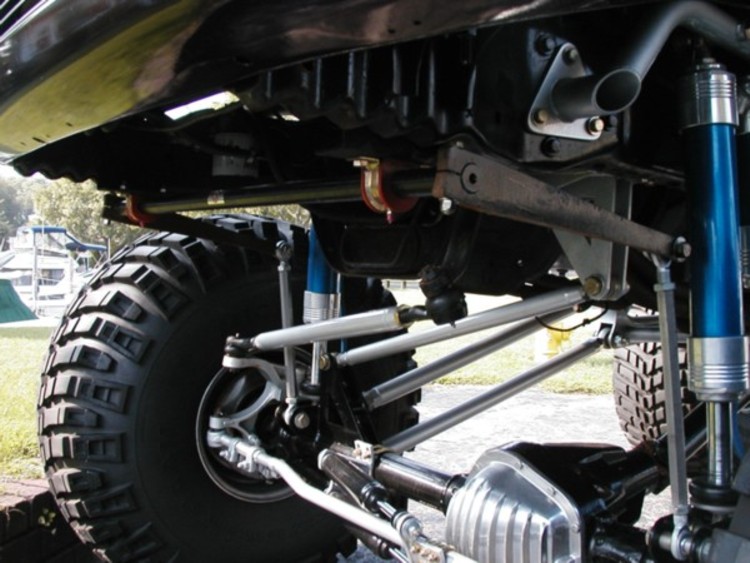 Underbody view of a lifted 4x4 front suspension with blue shocks and sway bar