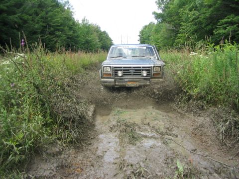 1986 Ford Bronco - This 1986 Ford Bronco navigates a muddy trail, kicking up spray as it goes.