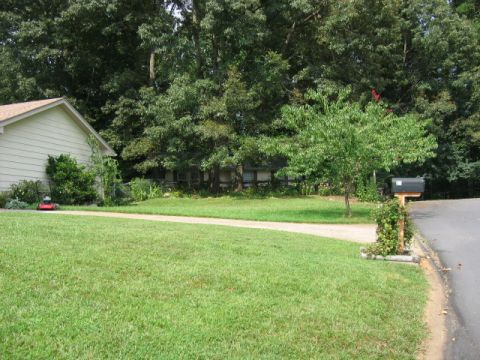 1985 Ford LTD Crown Victoria - A suburban house with a well-maintained lawn and a mailbox by the road.