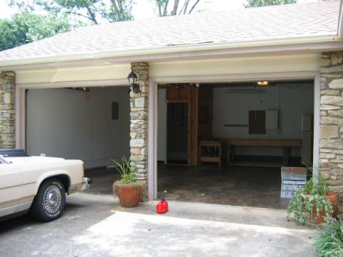 1985 Ford LTD Crown Victoria - A beige sedan is parked in front of an open garage with a workbench inside.