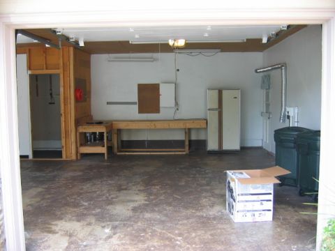1985 Ford LTD Crown Victoria - A view into a garage containing a workbench, refrigerator, and storage bins.
