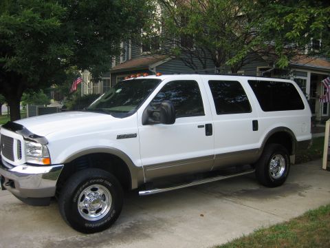 2003 Ford Excursion - This white 2003 Ford Excursion is shown from the front three-quarter angle, parked on a paved surface in front of a house.