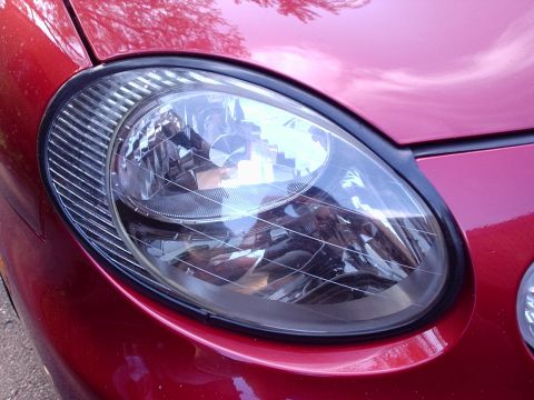 1998 Ford Taurus - Close-up of a red car's headlight assembly, showing intricate internal details and a ribbed bezel.