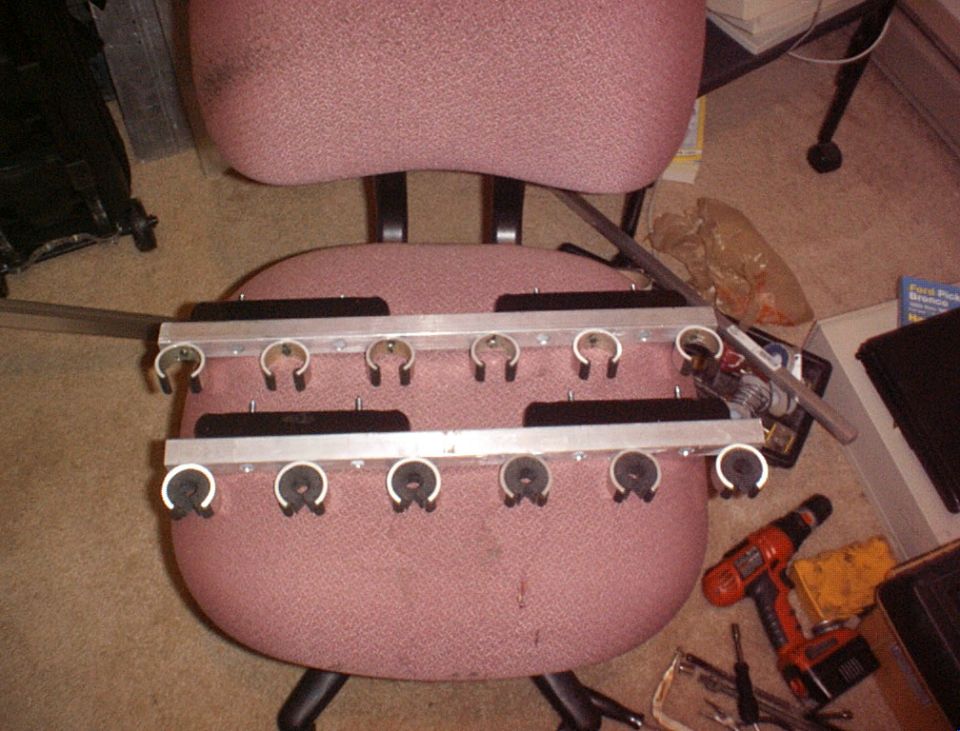 Metal rack with clips attached to a pink office chair, with a drill and other items on the floor