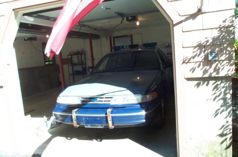 1991 Ford LTD Crown Victoria - Front view of a police car with a light bar, parked inside a garage.