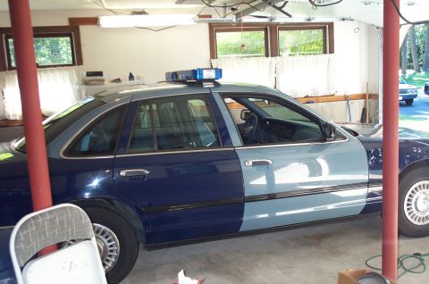 1991 Ford LTD Crown Victoria - A two-tone blue police car, likely a 1992 model, is parked inside a garage.