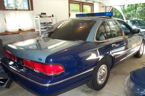 1991 Ford LTD Crown Victoria - A police car with a two-tone paint scheme is parked indoors, showing its rear and side profile.