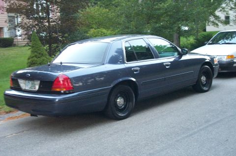 1991 Ford LTD Crown Victoria - A dark blue Ford Crown Victoria is parked on a residential street next to another vehicle.