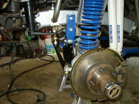 1995 Ford Bronco - Detail of a vehicle's suspension and braking system, showing a hub with a chrome cap and a rusty brake rotor.