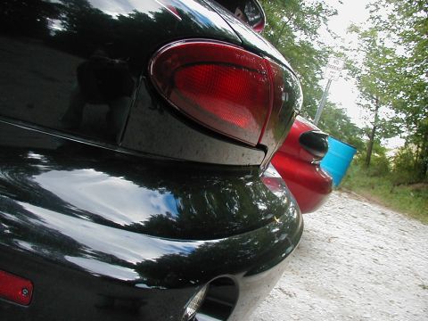 1997 Ford Taurus - Two cars parked on a gravel road with trees and a 'No Parking' sign visible.