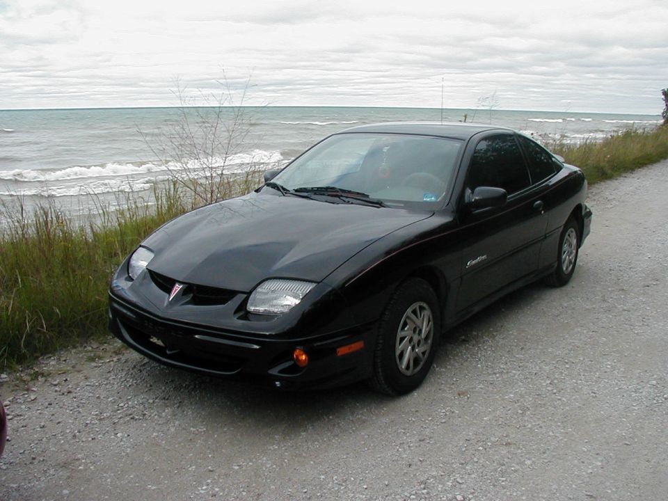 Black Pontiac Sunfire coupe parked by a lake