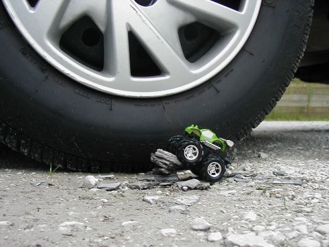 1997 Ford Taurus - A toy monster truck appears to be in peril as a massive tire looms over it.