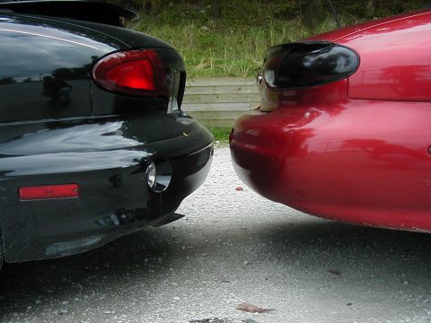 1997 Ford Taurus - Two cars parked close together, showing their rear ends and taillights.