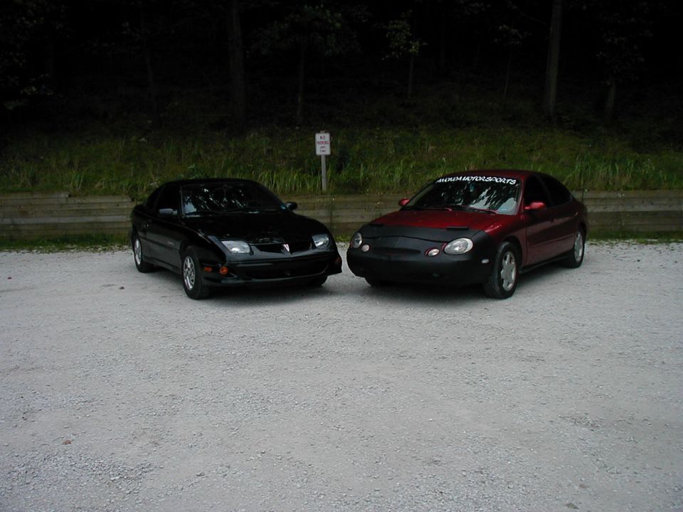 Black Pontiac Sunfire and red Ford Taurus parked side-by-side