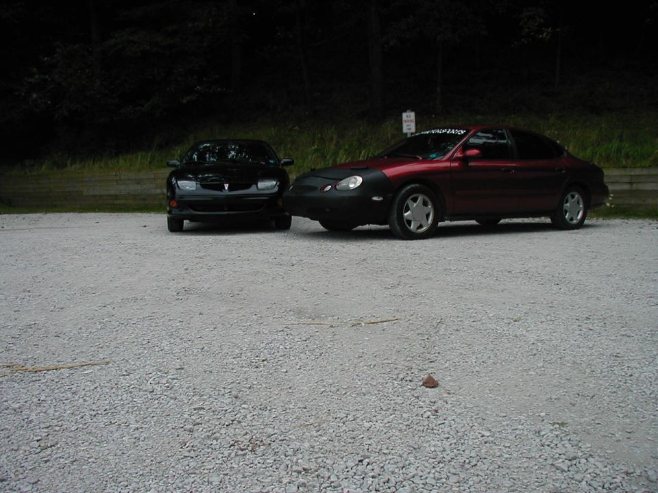 Maroon sedan with car bra parked next to black sedan