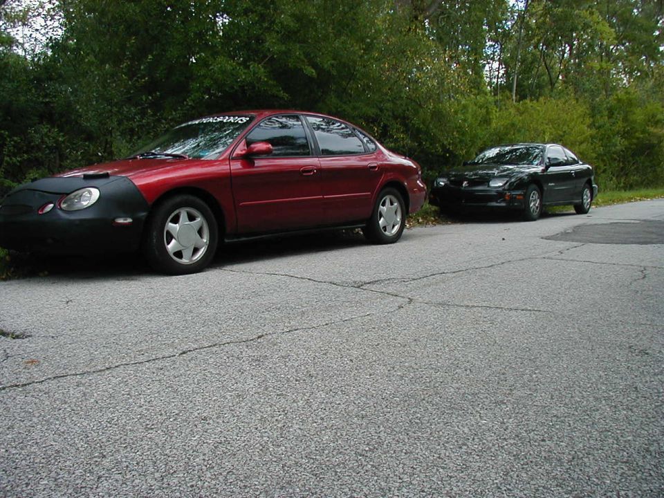 Red 1997 Ford Taurus with a black car bra parked on the side of a road