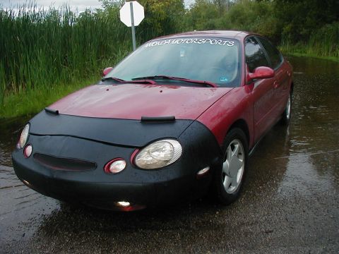 1997 Ford Taurus - A red sedan is parked in a flooded area, partially covered by a car bra.