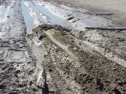 1989 Ford Bronco - A muddy track with deep ruts and puddles suggests off-road conditions.