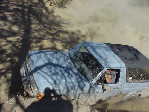 1989 Ford Bronco - A light blue SUV is stuck in thick mud, with a driver visible inside.