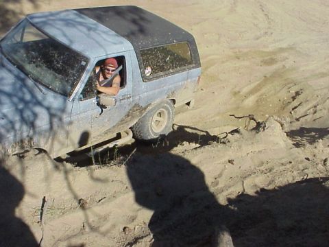 1989 Ford Bronco - This 1989 Ford Bronco navigates a sandy off-road trail with its driver visible behind the wheel.