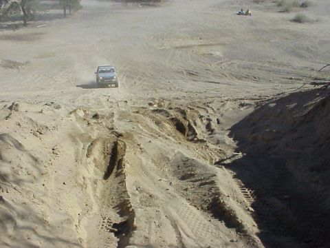 1989 Ford Bronco - 1989 Ford Bronco navigates a dusty, off-road terrain.