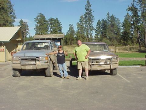 1989 Ford Bronco - Two men pose with their trucks on a sunny day. The truck on the left appears to be an older model SUV.
