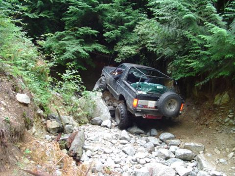 1993 Ford Bronco - This 1993 Ford Bronco is tackling a challenging rocky trail in a wooded area.