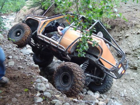 1993 Ford Bronco - Vehicle attempting to traverse a difficult rocky trail, with one side significantly higher than the other.