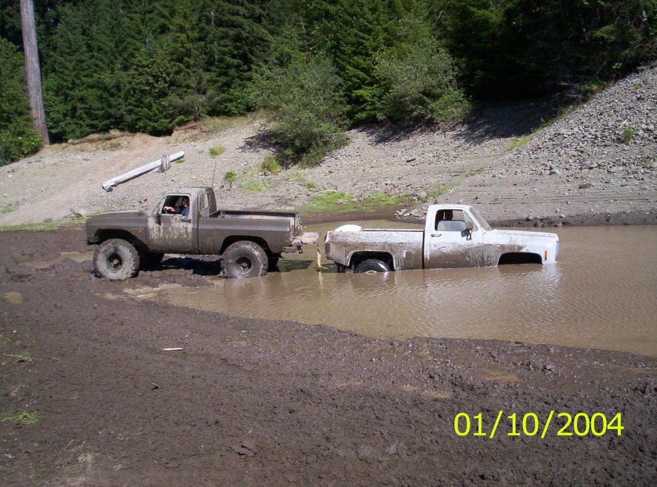 Two pickup trucks stuck in mud, one partially submerged