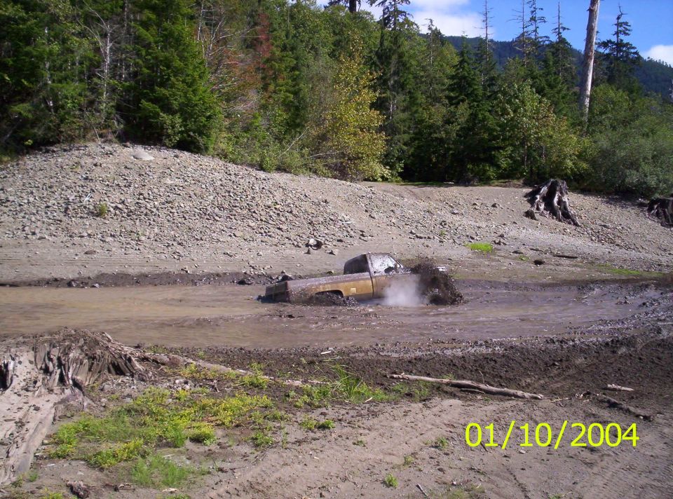 Brown pickup truck stuck in mud, splashing water