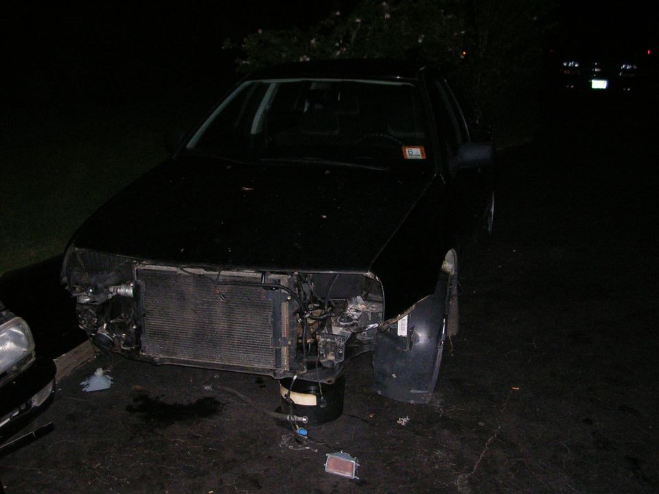 Black car with front bumper removed, radiator exposed, and damage to the driver's side fender